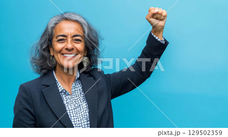 Middle aged latin american woman with raised fist symbolizing empowerment, strength and women solidarity, International Womens Day concept 129502359
