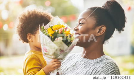 Mothers Day celebration with child giving flowers to smiling mother 129502438