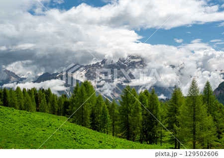 Mountain peaks around Cinque Torri in the Dolomites (Dolomiti, Dolomiten), Italy. Majestic summits partially covered in mist and clouds, with lush forests in the valleys below 129502606