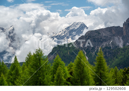 Mountain peaks around Cinque Torri in the Dolomites (Dolomiti, Dolomiten), Italy. Majestic summits partially covered in mist and clouds, with lush forests in the valleys below Mountain peaks around Cinque Torri in the Dolomites (Dolomiti, Dolomiten), Italy. Majestic summits partially covered in mist and clouds, with lush forests in the valleys below 129502608