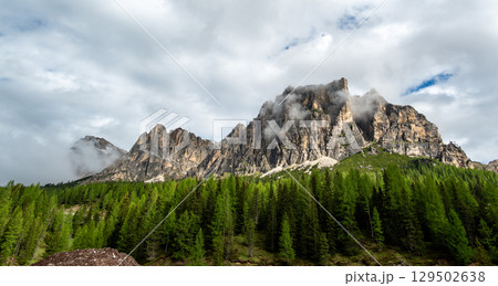 Mountain peaks around Cinque Torri in the Dolomites (Dolomiti, Dolomiten), Italy. Majestic summits partially covered in mist and clouds, with lush forests in the valleys below Mountain peaks around Cinque Torri in the Dolomites (Dolomiti, Dolomiten), Italy. Majestic summits partially covered in mist and clouds, with lush forests in the valleys below 129502638