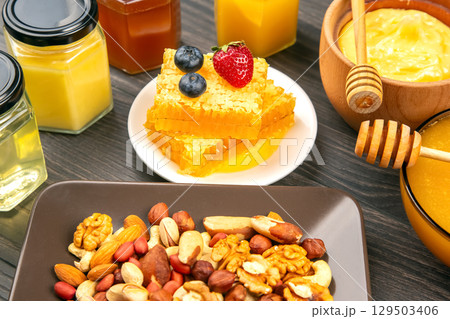 Delicious assortment of honey, fruits, and nuts on a wooden table for a healthy snack 129503406