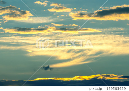 Beautiful sunset sky with clouds reflecting warm colors over the horizon 129503429