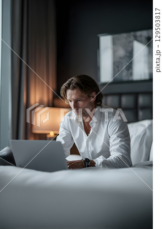 business traveler working on laptop in hotel room 129503817