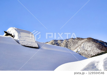東北地方の日本家屋と山の上に雪が積もっている風景 129504546