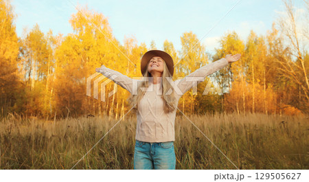 Happy smiling young woman in autumn park, joyful girl enjoying warm sunny weather, nature 129505627