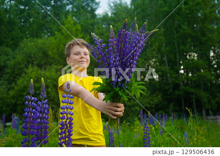 A joyful boy dressed in yellow is surrounded by blooming lupines, capturing a moment of happiness in a beautiful outdoor setting. A joyful boy dressed in yellow is surrounded by blooming lupines, capturing a moment of happiness in a beautiful outdoor setting. 129506436