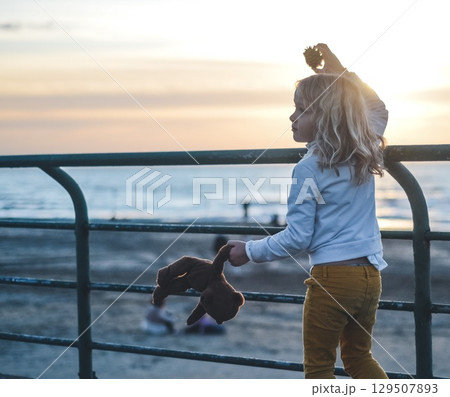 Child Watching Sunset on Beach Pier with Toy Child Watching Sunset on Beach Pier with Toy 129507893