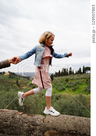 Child Balancing on Wall While Holding Adult Hand 129507903