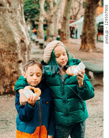 Kids Enjoying Doughnuts in Park on a Cool Day 129507908