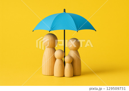 Wooden peg figurines representing a family standing under a blue umbrella on a yellow background symbolizing protection and security 129509731