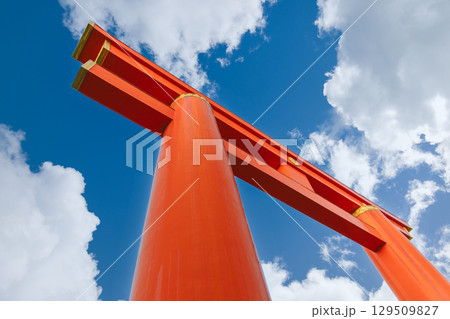 Heian-Jingu Shrine torii gate in Kyoto photographed from below against bright sky with white clouds 129509827