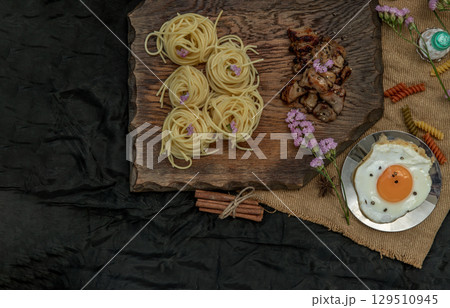 Spaghetti with Roasted Chicken with Black Pepper on a wooden plate Served with Fried Egg and Crispy butter toast. 129510945