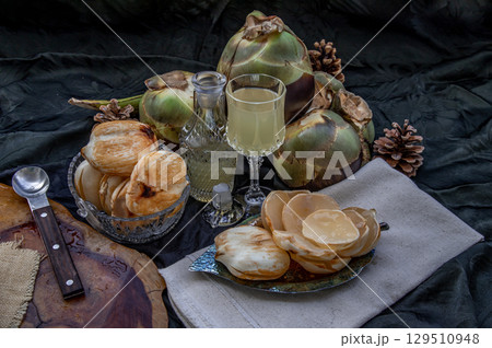 Peel toddy palm and fresh palm juice at front of dark background. 129510948