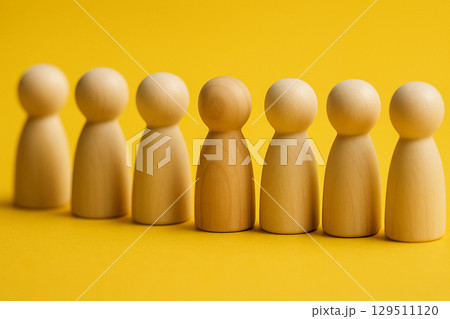 A row of natural figurines with a red figurine at the front symbolizing leadership and direction A row of natural figurines with a red figurine at the front symbolizing leadership and direction 129511120