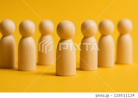 A red figurine leading a closely packed group of natural figurines symbolizing leadership and team alignment A red figurine leading a closely packed group of natural figurines symbolizing leadership and team alignment 129511124