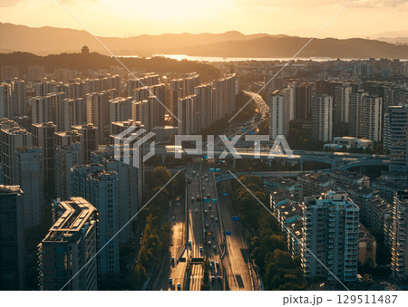 Aerial view of a residential buildings alongside a multilane highway interchange filled with moving vehicles 129511487