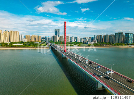 Aerial daytime view of cars and buses crossing Qiantang River Bridge in Hangzhou, China with city skyline. Aerial daytime view of cars and buses crossing Qiantang River Bridge in Hangzhou, China with city skyline. 129511497