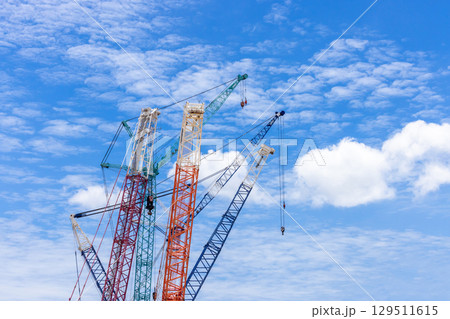 Crawler crane on blue sky white clouds background, Real estate industry. Red crawler crane use reel lift up equipment in construction site. Crane for rent. Crane dealership for construction business. Crawler crane on blue sky white clouds background, Real estate industry. Red crawler crane use reel lift up equipment in construction site. Crane for rent. Crane dealership for construction business. 129511615