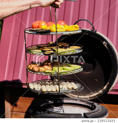 Grilling fresh vegetables and sausages on a sunny day at a backyard barbecue gathering Grilling fresh vegetables and sausages on a sunny day at a backyard barbecue gathering 129511833