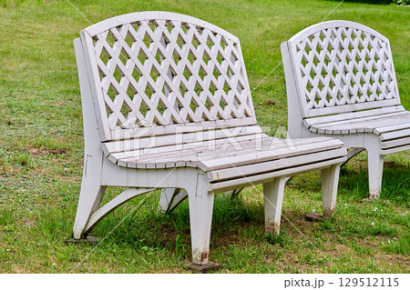 White wooden benches in a park setting under cloudy skies during the afternoon 129512115