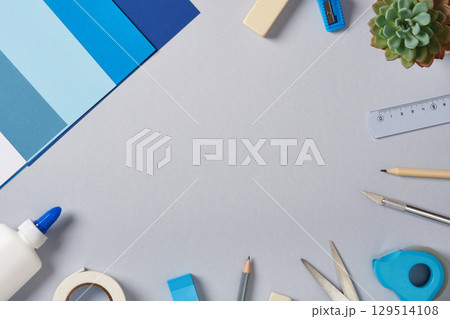 Top view of the paper crafts work table. Scissors, craft knife, pencil, glue, eraser, paper. Place for your text. 129514108
