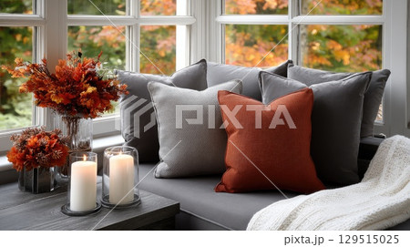 A living room adorned with fall decorations, featuring a soft grey sofa, cozy candles, and an autumn wreath to create a warm ambiance 129515025