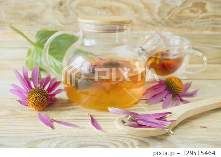 Echinacea flower tea in a glass teapot on a wooden background. Medicinal herbal tea from echinacea flowers. 129515464