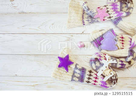 Christmas background. Knitted wool scarf with ornament on wooden background, illumination and handmade Christmas decorations. Top view with space for text. Christmas background. Knitted wool scarf with ornament on wooden background, illumination and handmade Christmas decorations. Top view with space for text. 129515515