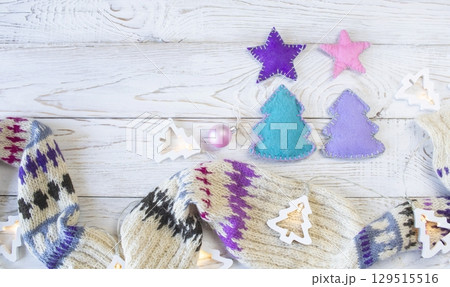 Christmas background. Knitted wool scarf with ornament on wooden background, illumination and handmade Christmas decorations. Top view with space for text. Christmas background. Knitted wool scarf with ornament on wooden background, illumination and handmade Christmas decorations. Top view with space for text. 129515516