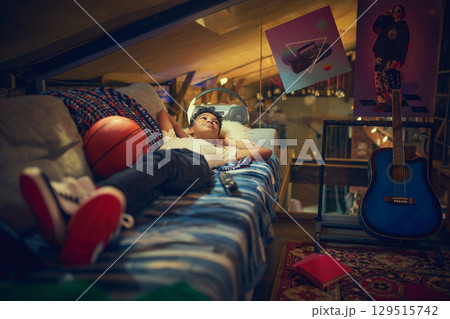 Boy daydreaming on sofa in vintage attic with basketball Boy daydreaming on sofa in vintage attic with basketball 129515742