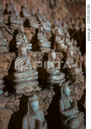 Large Buddha statue surrounded by smaller sculptures in Marble Mountains cave, Sacred cave temple with Buddha and statues in Marble Mountains Vietnam 129516286