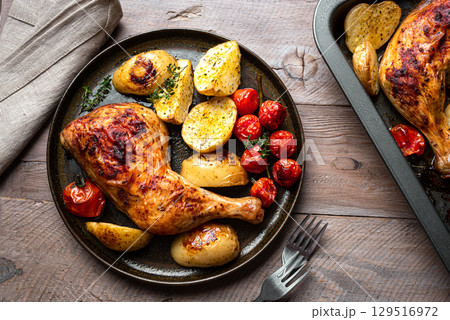 Oven roasted chicken leg quarter with potatoes, tomatoes 129516972