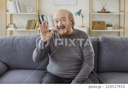 Senior man waves hello, having video call on laptop talking with relatives, smiling aged grandfather 129517433