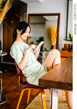 　スマホで友人とやりとりするカジュアルな女性 129517553