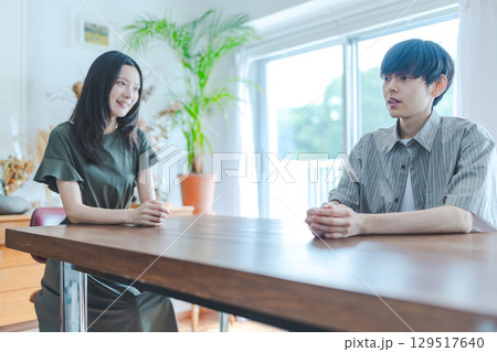 　窓辺で笑顔の男女の会話 129517640