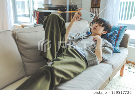 ソファで横になって動画を楽しむ男性 ソファで横になって動画を楽しむ男性 129517726