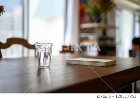 　テーブルに置かれたガラスのコップとノート 129517753