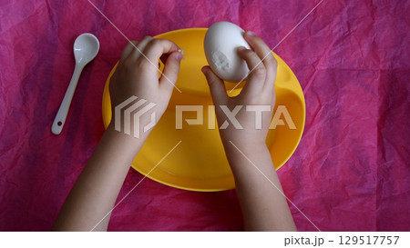 Toddler hands peel eggshell from Easter egg Toddler hands peel eggshell from Easter egg 129517757