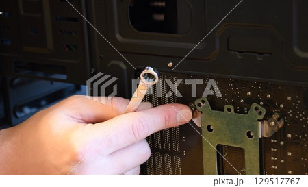 Male hand with metal wrench fix nut on bolt at computer motherboard 129517767