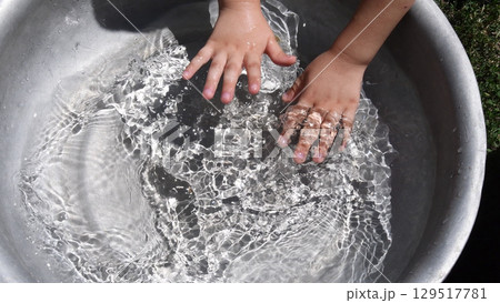 Kid washing hands in clear water inside basin. Summer fun Kid washing hands in clear water inside basin. Summer fun 129517781