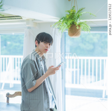 　窓辺のカウンターでスマホを持つ男性の朝時間 129517812