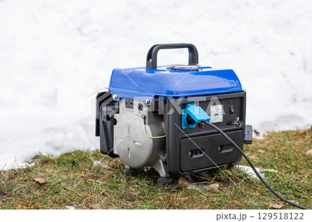 Small generator outdoors while producing electricity. Snow, cold, winter period, blackouts and autonomous supply by electric power 129518122