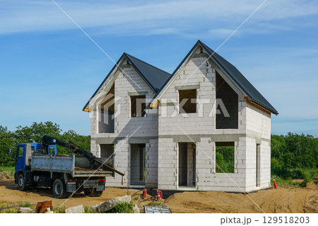 Two-Story House Under Construction with Concrete Blocks and Roof Installed 129518203