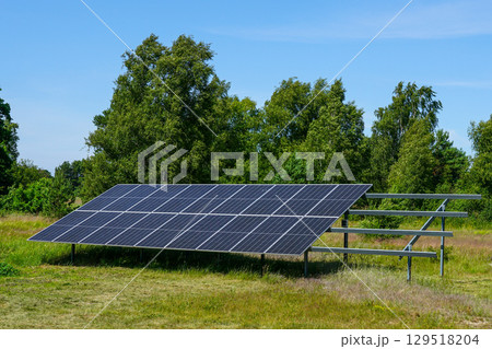 Solar Panel Installation in Green Field with Blue Sky Background 129518204