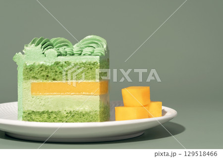 Layered bento cake featuring vibrant green pistachio and mango filling, garnished with whipped cream, served on a white plate, showcasing a delightful dessert concept with copy space Layered bento cake featuring vibrant green pistachio and mango filling, garnished with whipped cream, served on a white plate, showcasing a delightful dessert concept with copy space 129518466