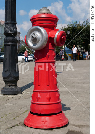 Red fire hydrant stands on a city street 129518550