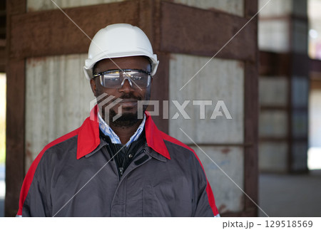 African american workman stands at construction site and looks at camera African american workman stands at construction site and looks at camera 129518569
