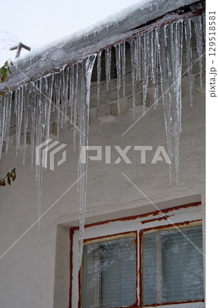 Large long icicles hang from roof of house Large long icicles hang from roof of house 129518581