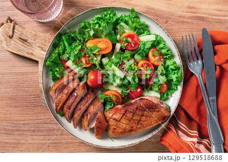 Delicious grilled duck breast served with fresh garden salad and cherry tomatoes at a rustic dining table Delicious grilled duck breast served with fresh garden salad and cherry tomatoes at a rustic dining table 129518688